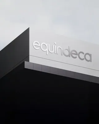 Carrusel de aplicaciones de la identidad de Equindeca: señalética de fachada, camión rotulado en violeta, señal colgante de bodega, pictogramas, patrón geométrico, mano girando un dial, rejilla de acero grabada y pantalla con el isotipo