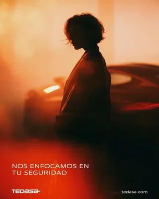 Silueta de una mujer a contraluz frente a un auto entre luz naranja y bruma