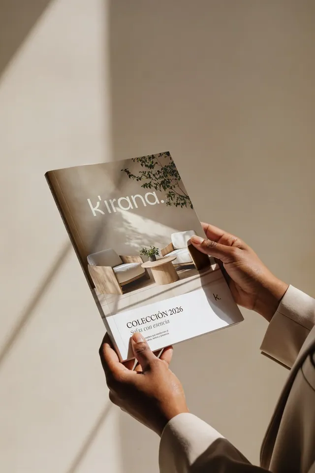 Catálogo Colección 2026 de Kirana sostenido en la mano, con fotografía de interiores