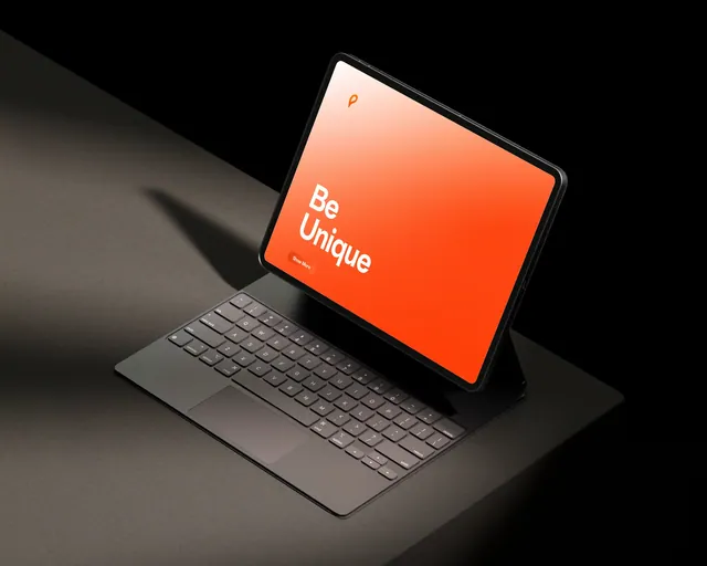 Tablet con teclado que muestra una landing naranja con el texto Be Unique.