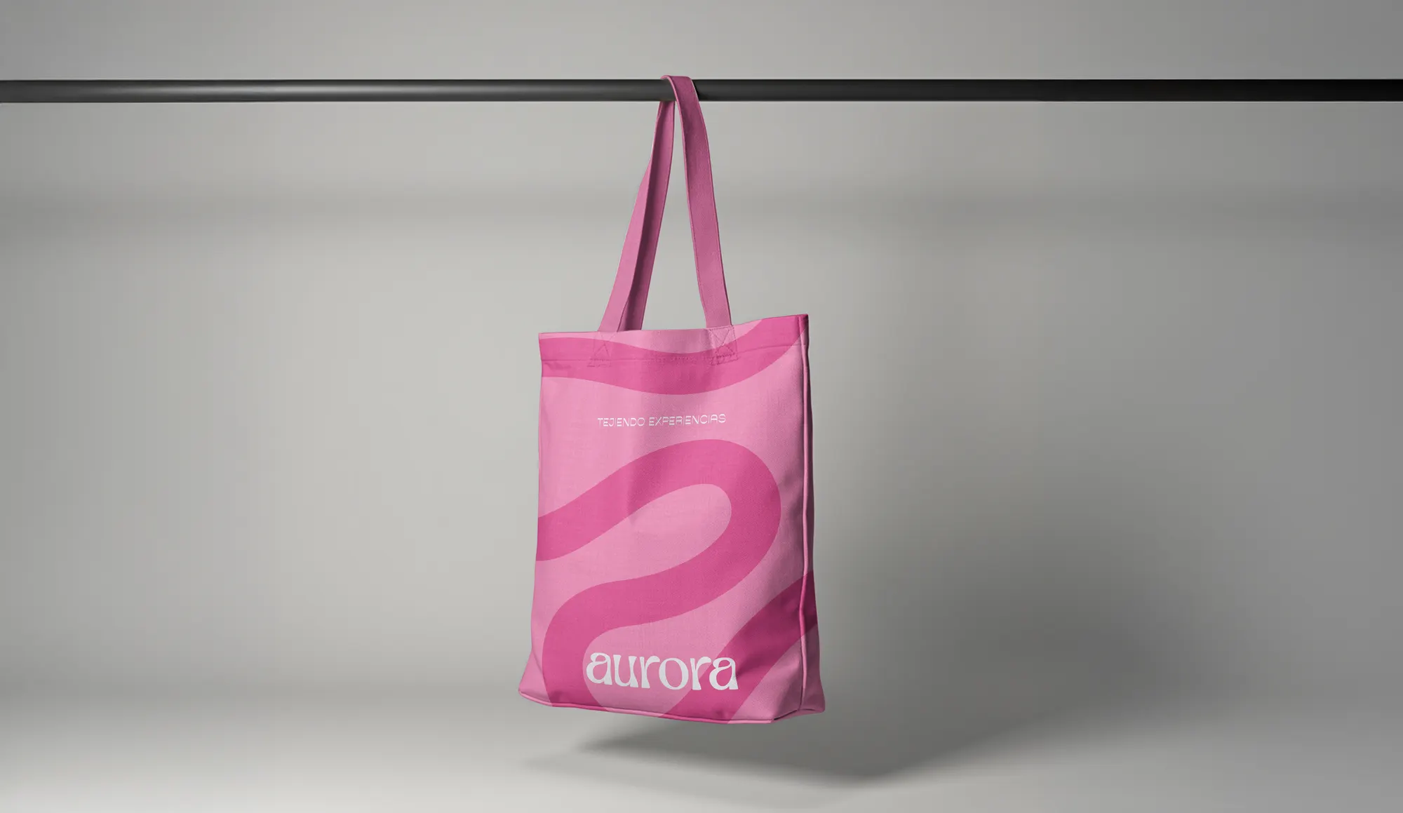 Tote bag de Aurora colgado, con el wordmark de la marca sobre fondo neutro