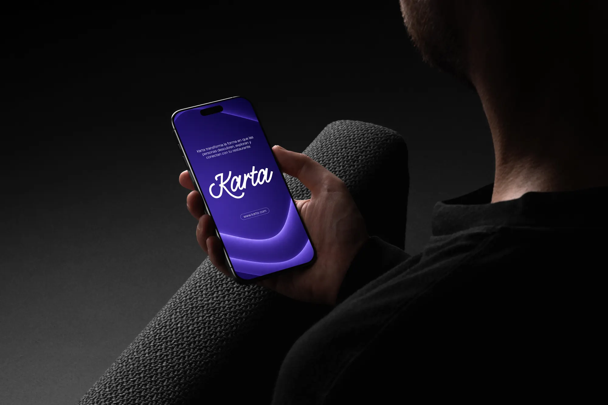 Persona sosteniendo un teléfono con la app de Karta abierta, en tema violeta