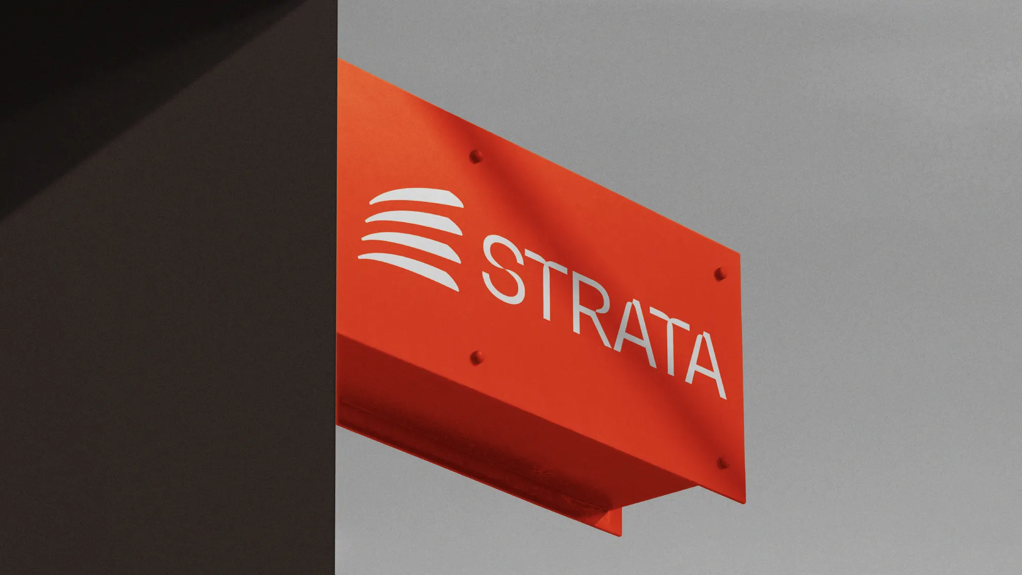 Empaque de Strata en naranja y gris con el logotipo, fotografiado en ángulo